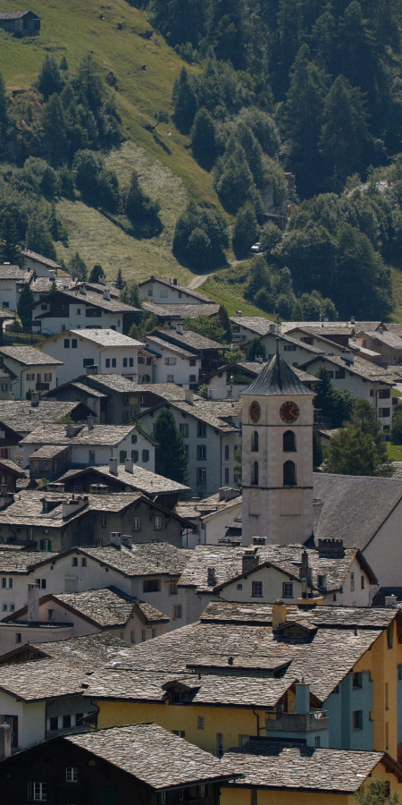 Sommertag im Bergdorf Vals mit Blick auf die traditionelle Bauweise und grüne Hügel (Foto: © 7132 Hotel / Julien Balmer) Bergdorf Vals im Sommer mit grünen Wiesen und typischen Steindächern