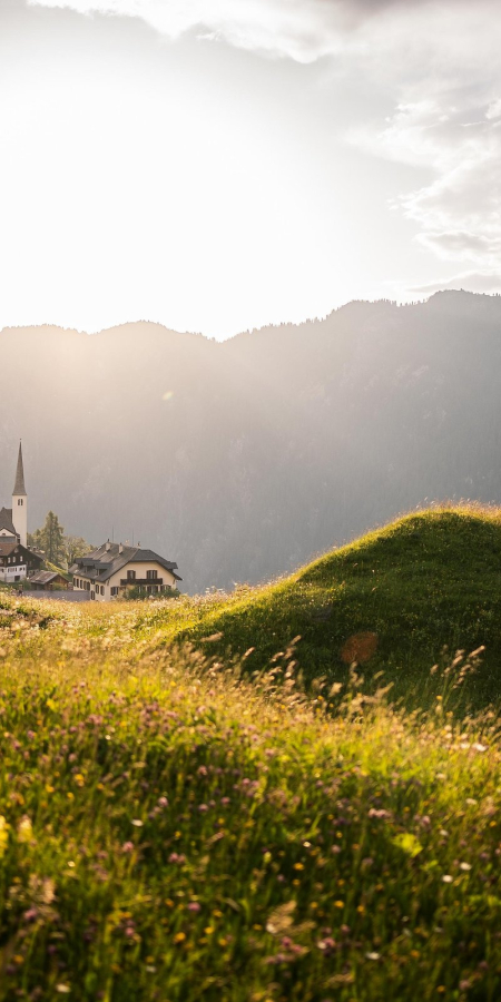 Abendstimmung im Safiental: Das Bergdorf Tenna liegt idyllisch eingebettet zwischen blühenden Wiesen und imposanten Bergen (Foto: © Marco Hartmann) Blick auf das Bergdorf Tenna im Safiental bei Sonnenuntergang