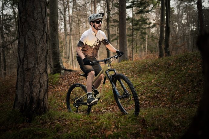 Stylisch auf dem Trail: Das Bikeshirt «Home of Trails» für Herren – erhältlich im Fanshop von Graubünden Ferien (Foto: © Marco Hartmann) Mountainbiker trägt das Bikeshirt «Home of Trails» aus dem graubünden-Fanshop auf einem Waldtrail