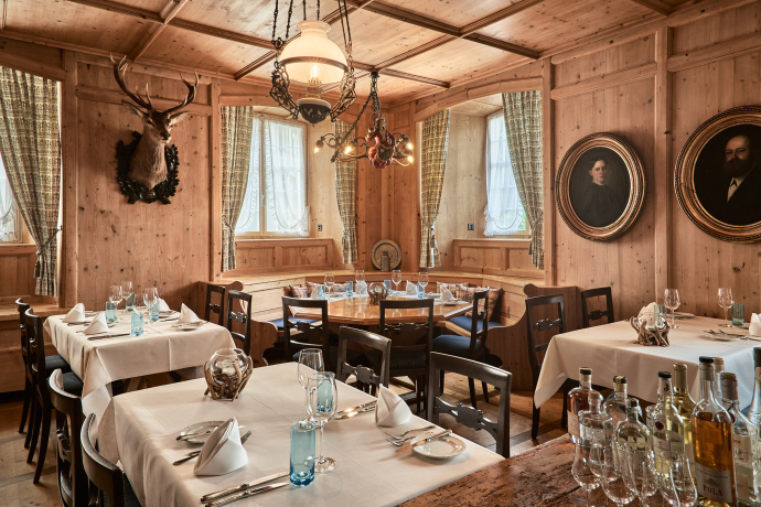 Alpiner Charme mit einem Hauch Noblesse – die Zollstube verbindet Heimatgefühl mit Kulinarik auf höchstem Niveau (Foto: © Grand Resort Bad Ragaz) Stilvoll eingedeckter Gastraum mit Holzvertäfelung im Restaurant Zollstube in Bad Ragaz