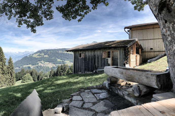 Maiensäss Rameidels in Fideris auf 1250 m ü. M. an aussichtsreicher Lage mit Sitzplatz und Brunnen (Fotoquelle: OpenBooking) Maiensäss Rameidels in Fideris mit Panoramablick über das Prättigau und Brunnen im Vordergrund