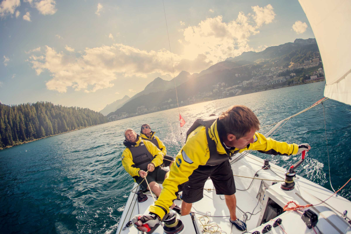 Im Engadin trifft sich regelmässig die internationale Elite der Segelwelt (Foto: © Engadin Tourismus AG / Filip Zuan) Drei Männer mit Schwimmwesten auf einem Segelboot auf dem St. Moritzersee