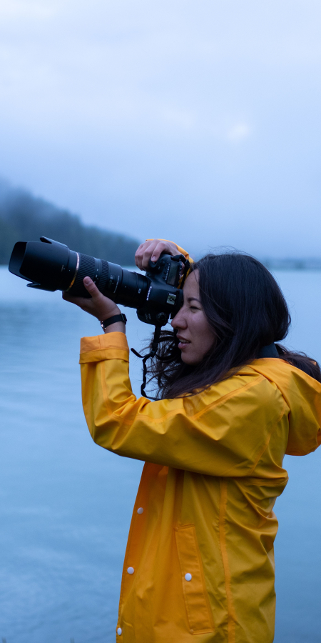 Frau mit Kamera vor einem See