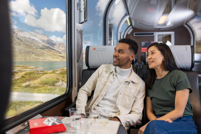 On board the Bernina Express – panoramic journey with views of Lago Bianco (Photo: © Rhaetian Railway / Nicola Pitaro) Two travellers on the Bernina Express look out the panoramic window at Lago Bianco and the mountains of Graubünden