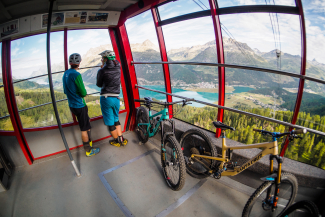 Entspannt zum Gipfel: Mountainbiken im Engadin (Fotoquelle: Engadin) Mountainbiker mit Velos in einer Gondel geniessen die Aussicht auf Seen und Berge