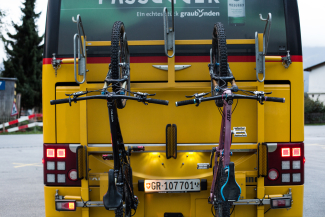 Mountainbike-Transport mit dem Postauto in Graubünden Zwei Mountainbikes sind am Heck eines gelben Postautos in Graubünden befestigt